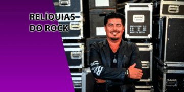 O empresário Paulo Baron sorrindo de braços cruzados à frente de cases de equipamentos de som pretos. À esquerda, um bloco roxo com o texto "RELÍQUIAS DO ROCK".