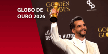 Wagner Moura sorridente segurando a estatueta dourada do Globo de Ouro. Ele veste um terno branco. À esquerda, um bloco bordô com o texto "GLOBO DE OURO 2026".