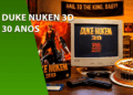 Foto de um setup retro gamer celebrando os 30 anos de Duke Nukem 3D. Sobre uma mesa de madeira, há um monitor CRT antigo exibindo o menu do jogo, uma caixa original de Duke Nukem 3D, um bolo de aniversário com a inscrição "1996-2026", óculos escuros, um disquete e uma réplica de pistola. Ao fundo, um banner diz "Hail to the King, Baby!".