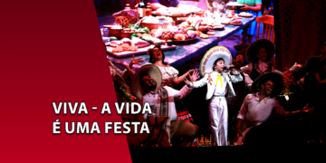 Elenco de músicos e cantores caracterizados com trajes típicos mexicanos e sombreros em uma performance teatral. À esquerda, uma faixa vermelha inclinada com o texto "VIVA - A VIDA É UMA FESTA".