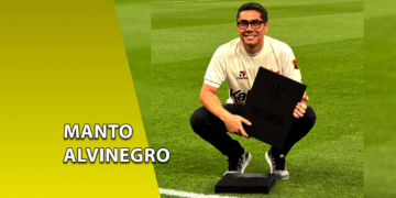 Homem sorridente ajoelhado em um campo de futebol, vestindo uma camisa branca retrô do Corinthians e segurando o livro "Manto Alvinegro". À esquerda, uma faixa amarela inclinada com o texto "MANTO ALVINEGRO".