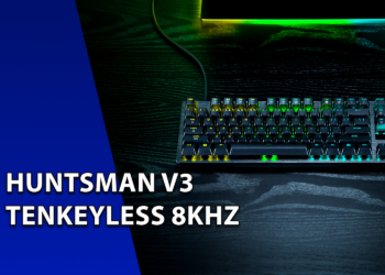 Teclado mecânico gamer Razer Huntsman V3 Tenkeyless com iluminação RGB verde sobre uma mesa de madeira escura. À esquerda, uma faixa azul inclinada com o texto "HUNTSMAN V3 TENKEYLESS 8KHZ".