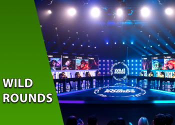 Palco principal da Riot Games Arena decorado com luzes azuis e os telões do torneio Wild Rounds exibindo campeões de League of Legends. À esquerda, uma faixa verde inclinada com o texto "WILD ROUNDS".