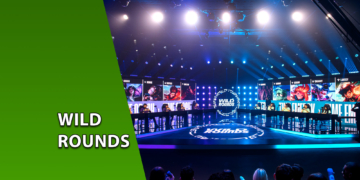 Palco principal da Riot Games Arena decorado com luzes azuis e os telões do torneio Wild Rounds exibindo campeões de League of Legends. À esquerda, uma faixa verde inclinada com o texto "WILD ROUNDS".