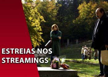 Homem de casaco escuro segurando uma sacola de papel em um gramado ao ar livre, olhando para um túmulo com flores, enquanto uma mulher o observa ao fundo. À esquerda, uma faixa vermelha inclinada com o texto "ESTREIAS NOS STREAMINGS".