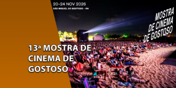 Plateia sentada em espreguiçadeiras na areia da praia assistindo a uma projeção noturna ao ar livre durante a Mostra de Cinema de Gostoso. À esquerda, uma faixa marrom inclinada com o texto "13ª MOSTRA DE CINEMA DE GOSTOSO".